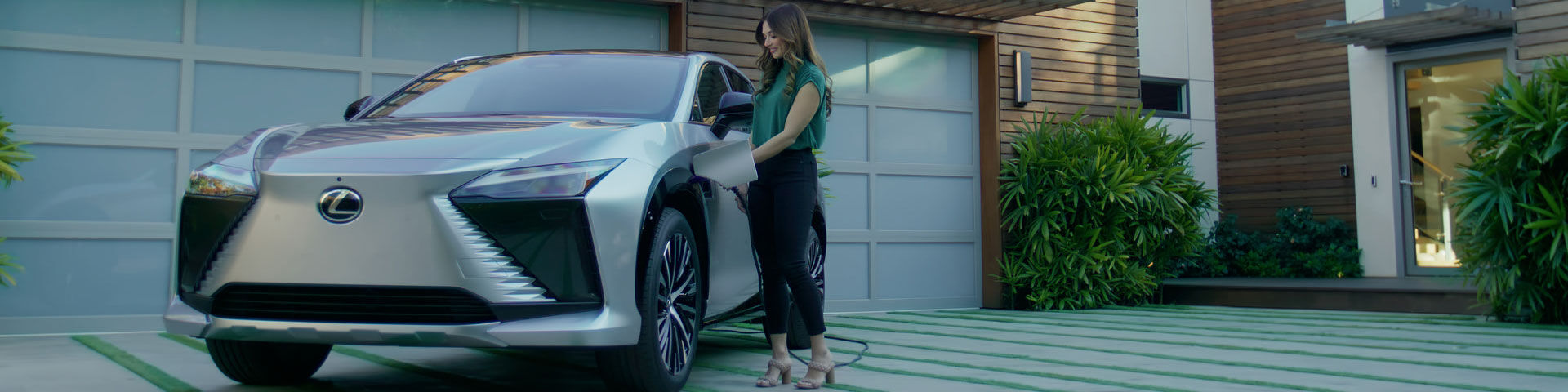 Woman charging Lexus RZ outside a house