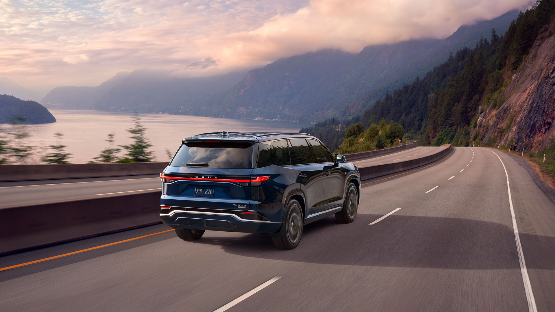 2025 Lexus TX 500 Hybrid shown in Nightfall Mica driving on a highway