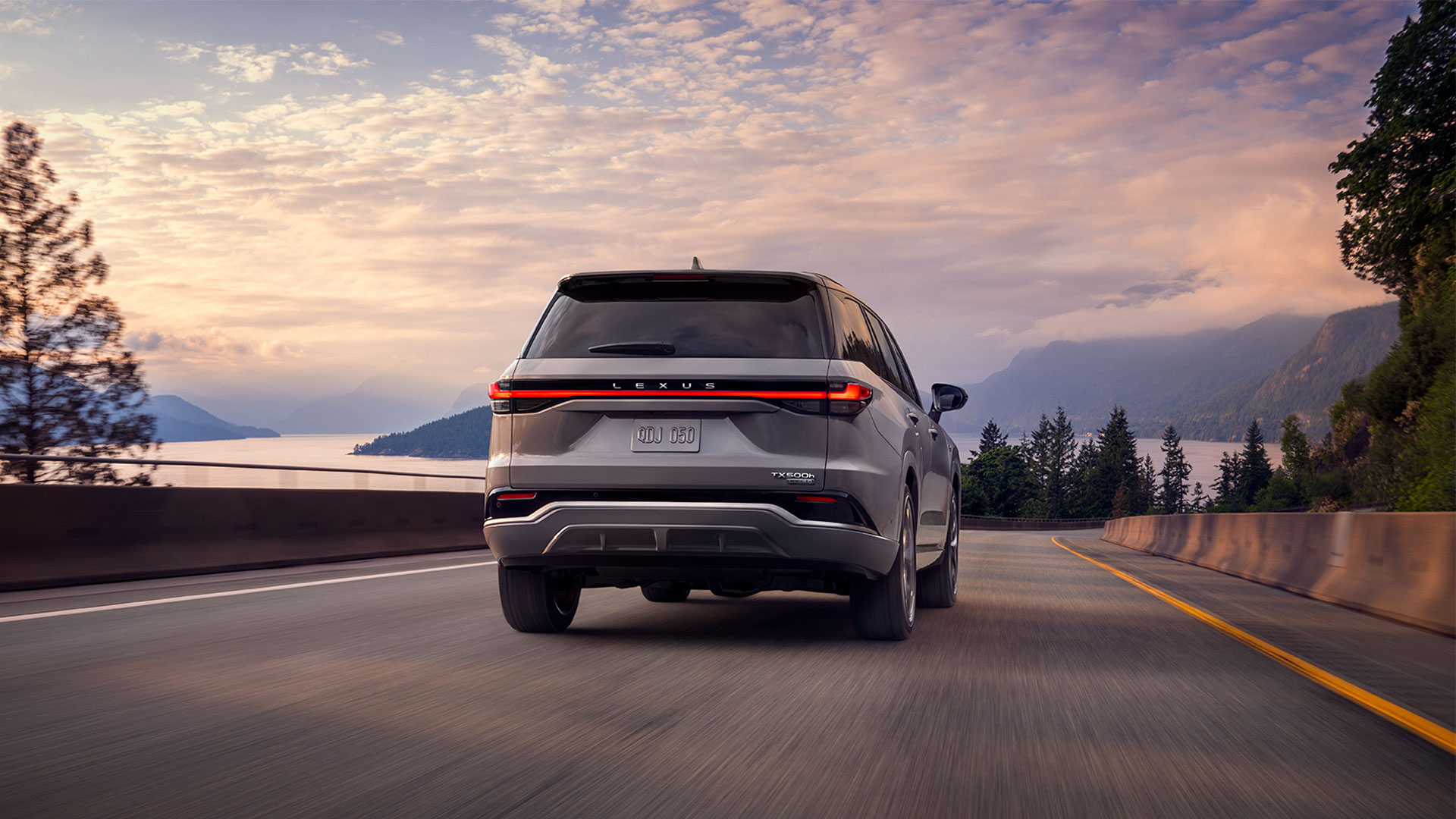 2025 TX 500 Hybrid Incognito driving on a road with the ocean in the background