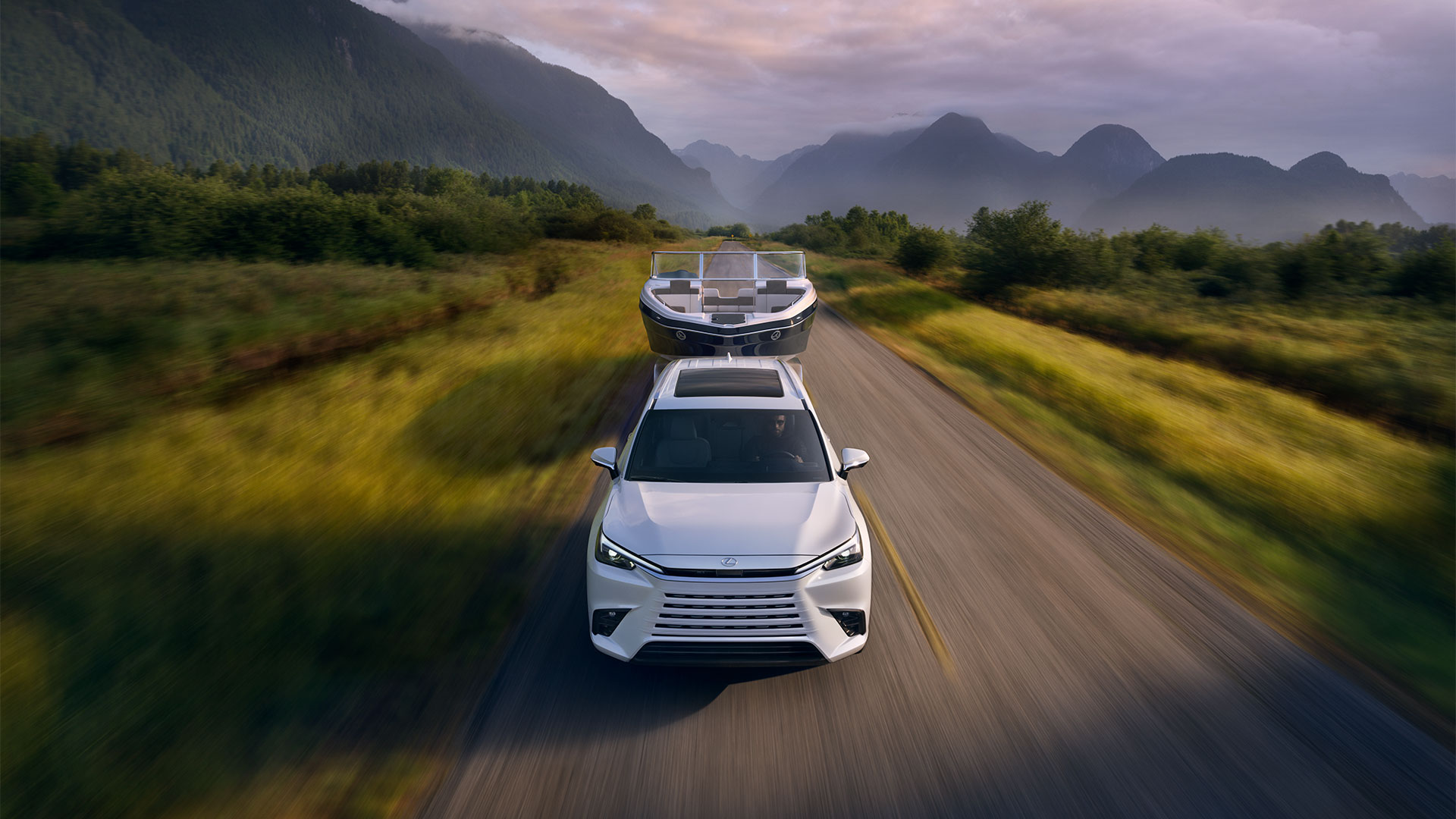 2026 TX 350 shown in Wind Chill Pearl towing a boat on a road with the mountains behind