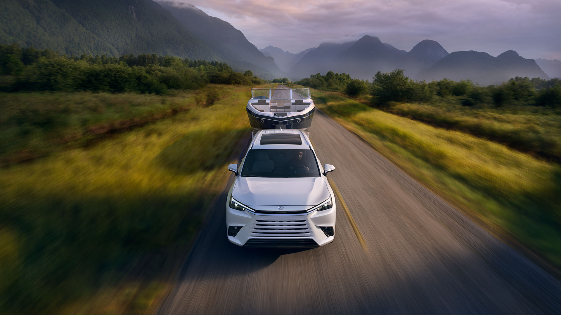 2025 TX 500 Hybrid Wind Chill Pearl towing a boat on a road with the mountains behind